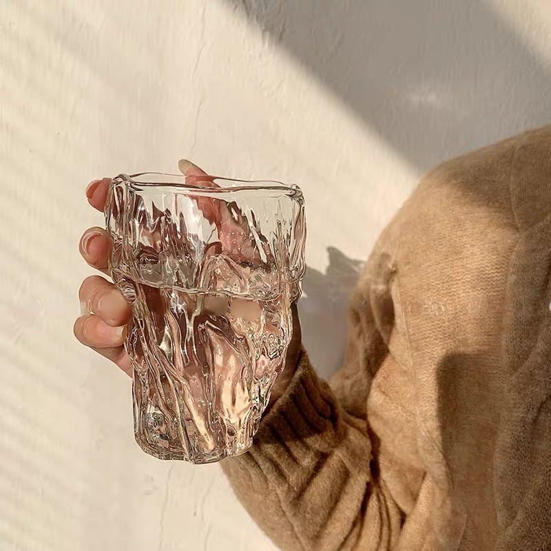 Hand holding a Crystal Wave Glass with a beautiful, rippled design that mimics the surface of crystal-clear water, perfect for adding elegance to your drinkware collection. Nest Haven Shop, GLASS, KITCHEN