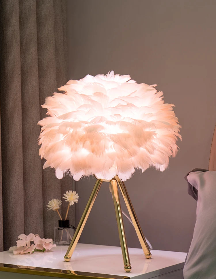 Soft and fluffy Feather Glow Lamp with a feather shade and gold legs, perfect for adding a warm and whimsical ambiance to any room. Shop now at Nest Haven Shop for your BEDROOM, KID'S ROOM, or LIVING ROOM.