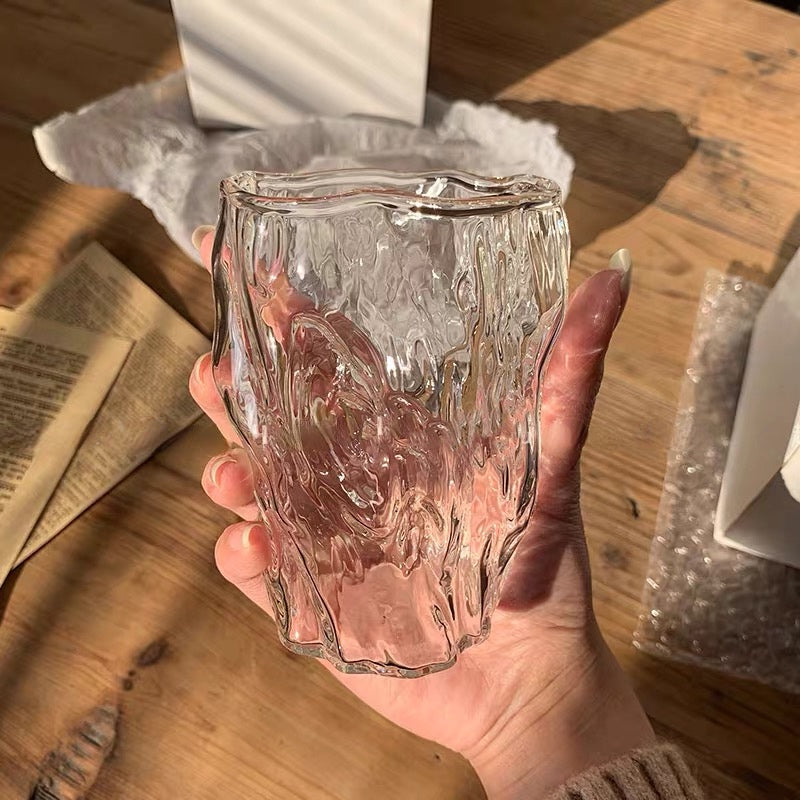 Hand holding the Crystal Wave Glass with its mesmerizing, rippled surface that looks like crystal-clear water, adding elegance to any drinkware collection from Nest Haven Shop. GLASS, KITCHEN