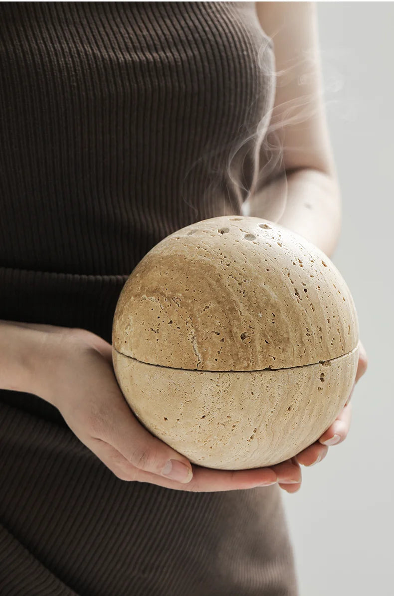 Person holding a travertine "Aroma Sphere" incense burner, perfect for home décor and gifts, ideal for meditation, yoga, purification, and aromatherapy. Fits various incense types with its bowl shape design. Nest Haven Shop, CERAMIC, BEDROOM, OFFICE, BATHROOM, LIVING ROOM.