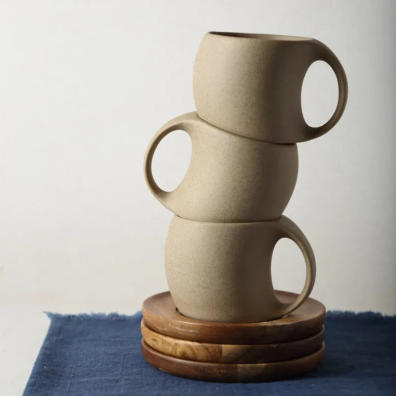 Stacked ceramic coffee cups with wooden saucers on a blue cloth. Nest Haven Shop, KITCHEN