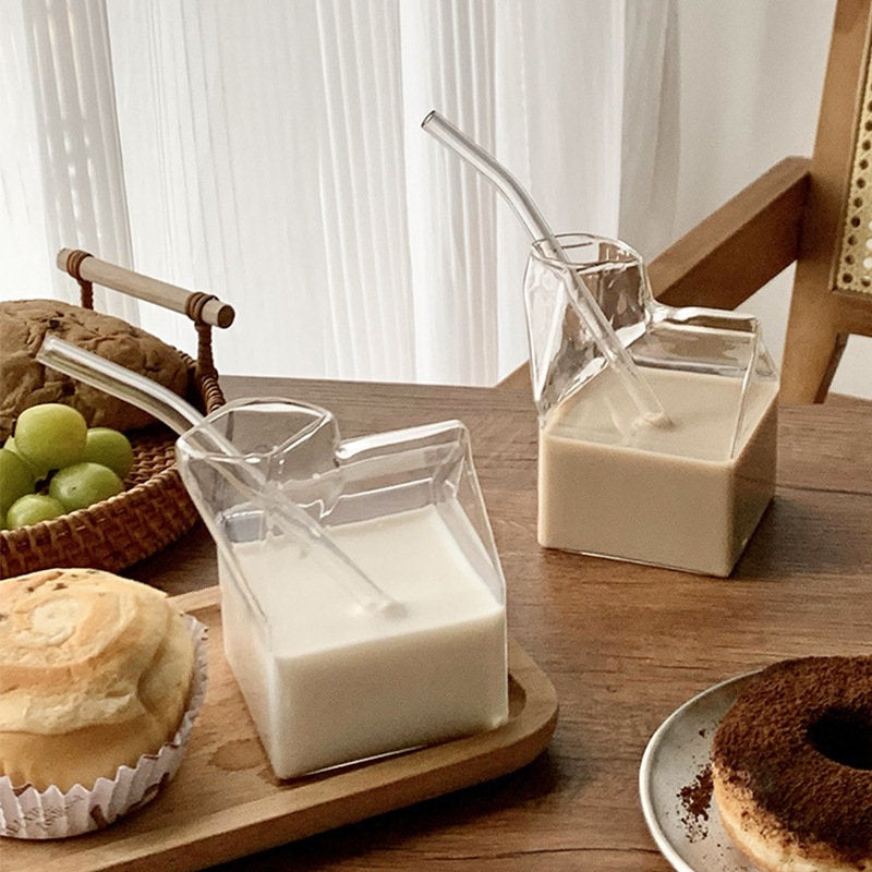 Two glass milk carton-shaped beverage containers filled with milk and coffee, alongside breakfast pastries on a wooden table. Nest Haven Shop, GLASS, KITCHEN