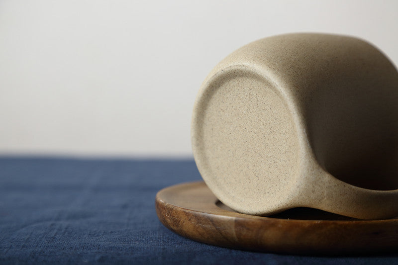 Rustic ceramic coffee cup with a wooden saucer, showcasing a modern handle design and earthy tones. Perfect for any cozy coffee moment or as a stylish home accent. Nest Haven Shop, KITCHEN